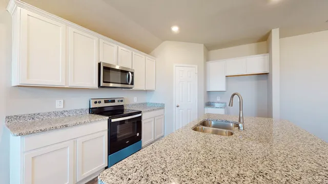 a kitchen with granite countertop a stove a sink and a microwave