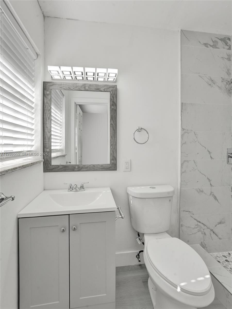 5657 Grant Street Hollywood, FL 33021 - Photo 29 of 59 a bathroom with a toilet sink vanity and mirror