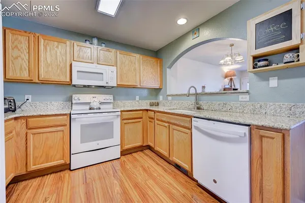 a kitchen with stainless steel appliances granite countertop a sink cabinets and wooden floor