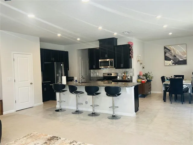 a kitchen with stainless steel appliances kitchen island granite countertop a refrigerator and a stove top oven