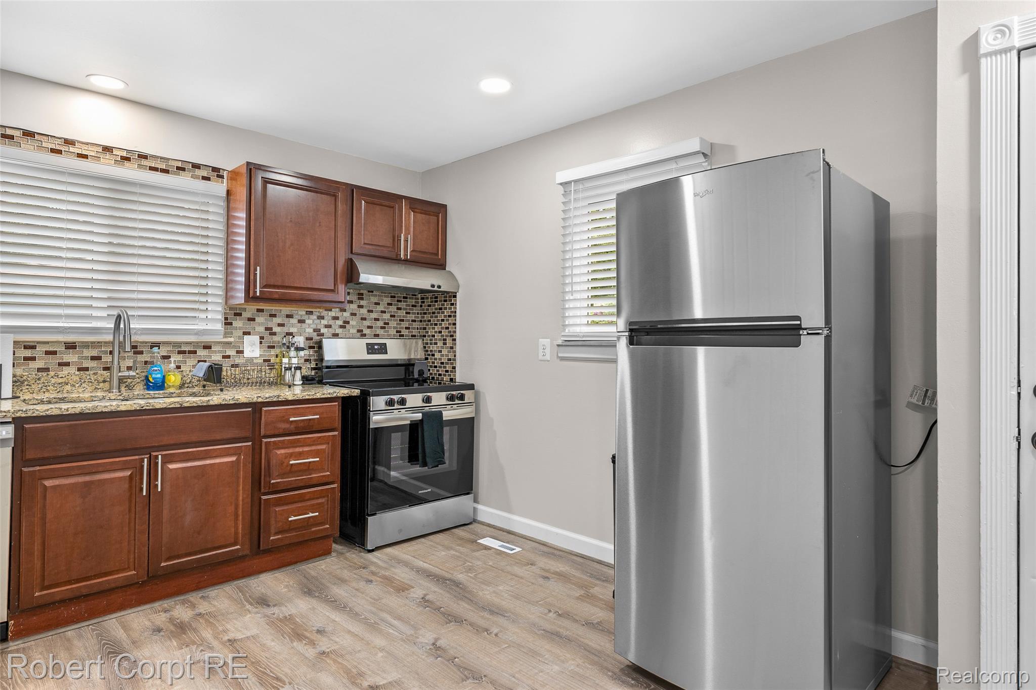 4772 Harding Street Dearborn Heights, MI 48125 - Photo 5 of 22 Kitchen featuring stainless steel appliances, light stone counters, light wood-style flooring, and backsplash