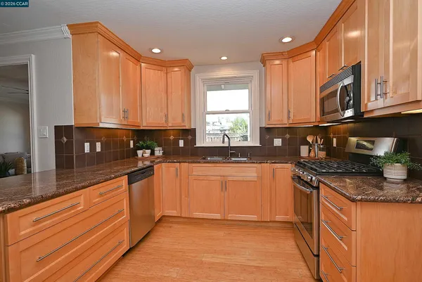 a kitchen with stainless steel appliances granite countertop a stove a sink and a microwave