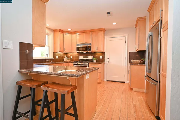 a kitchen with stainless steel appliances granite countertop a refrigerator and a stove top oven