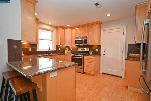 a kitchen with stainless steel appliances granite countertop a refrigerator a stove and a sink with wooden floor