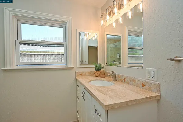 a bathroom with a granite countertop sink and a mirror