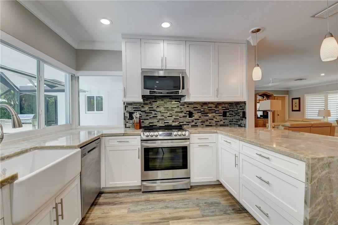 1163 Mulberry Way Boca Raton, FL 33486 - Photo 46 of 66 a kitchen with granite countertop a sink stainless steel appliances and cabinets