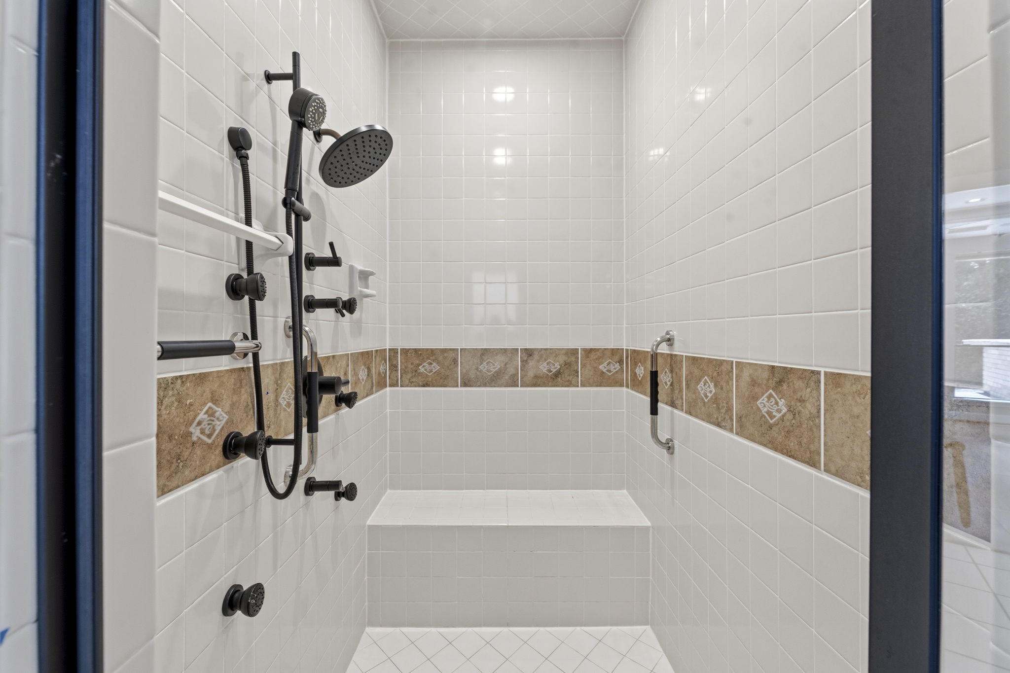 18503 Cabaniss Circle Spring, TX 77379 - Photo 28 of 49 Oversized walk-in shower with bench seating, multiple shower and spray heads, and grab bars for added comfort and accessibility.