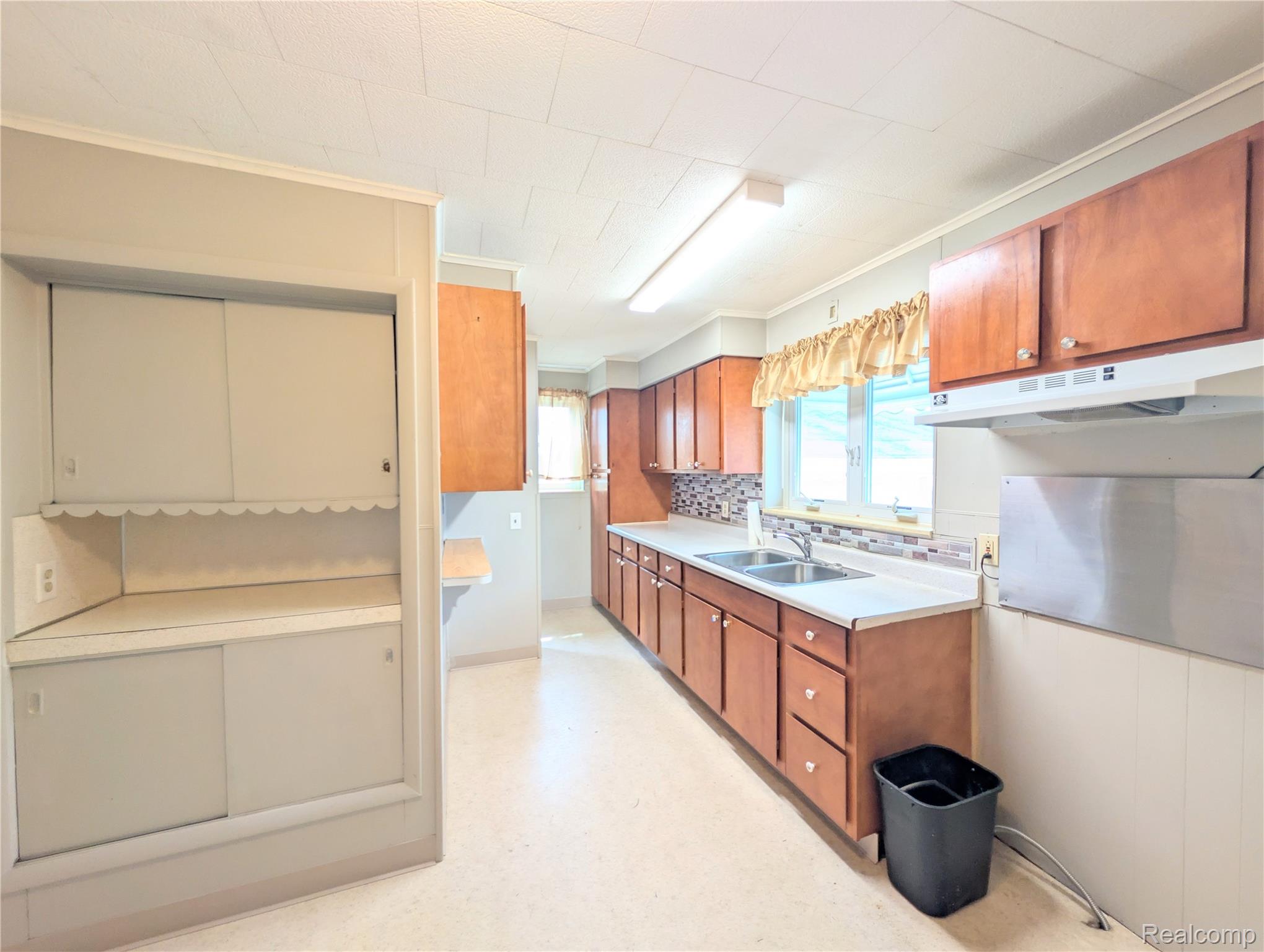 2173 West Mount Morris Road Mount Morris, MI 48458 - Photo 2 of 18 Galley-style kitchen featuring wood-finish cabinetry, stainless steel appliances, laminate countertops, and fluorescent overhead lighting