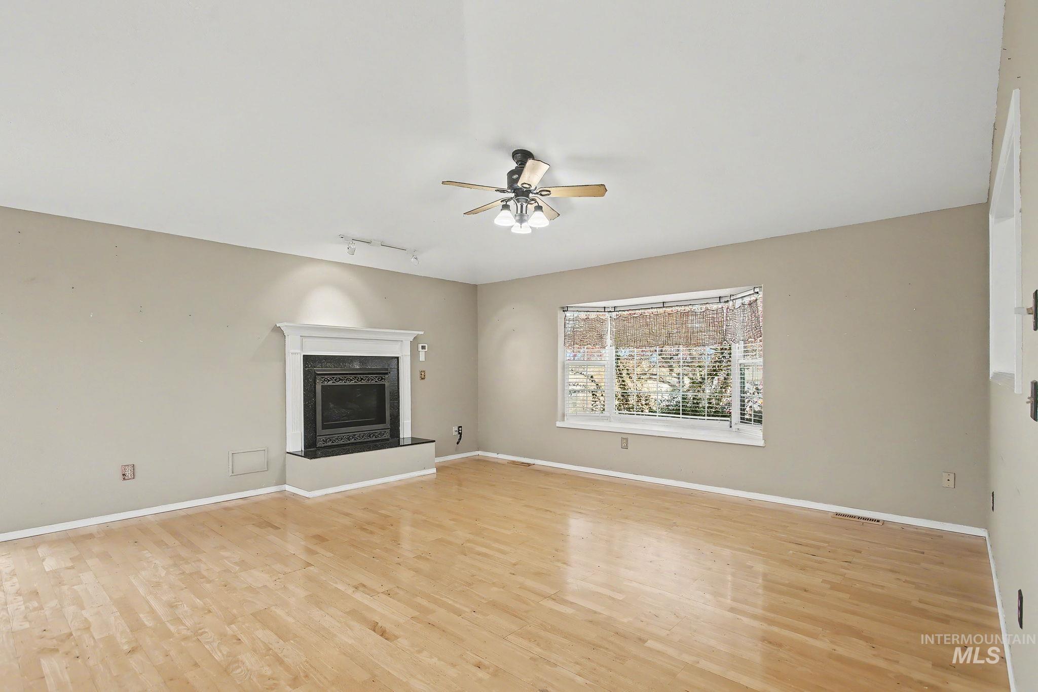 2242 Chukar Lane Clarkston, WA 99403 - Photo 7 of 41 Unfurnished living room featuring a fireplace, rail lighting, light wood finished floors, and a ceiling fan