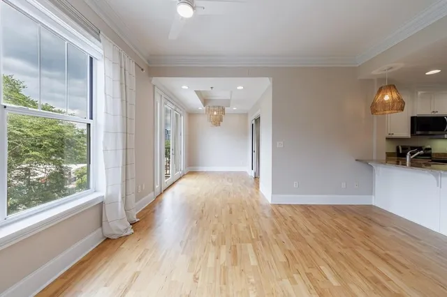 a view of empty room with wooden floor and fan
