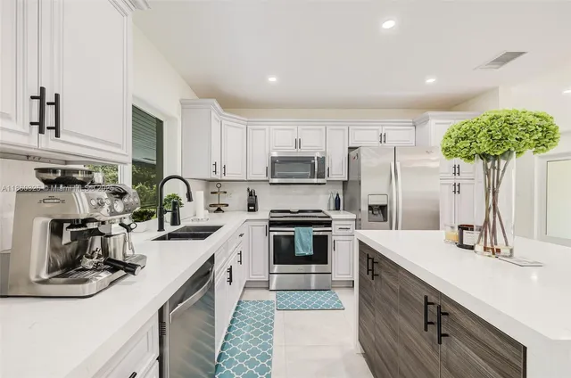 a kitchen with kitchen island granite countertop a sink stainless steel appliances and white cabinets