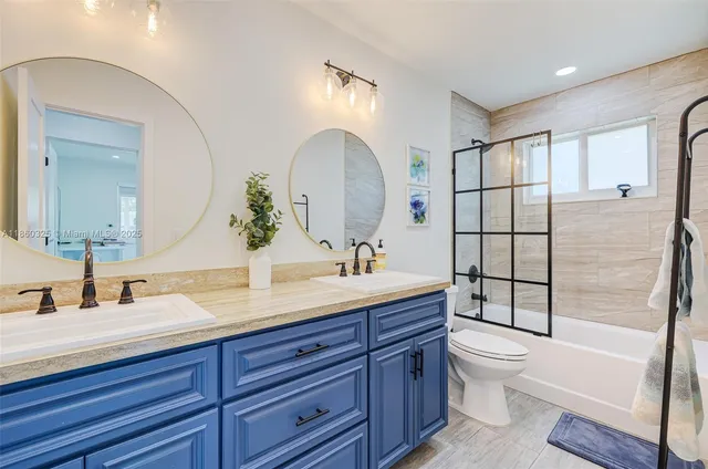 a bathroom with a double vanity sink toilet mirror and shower