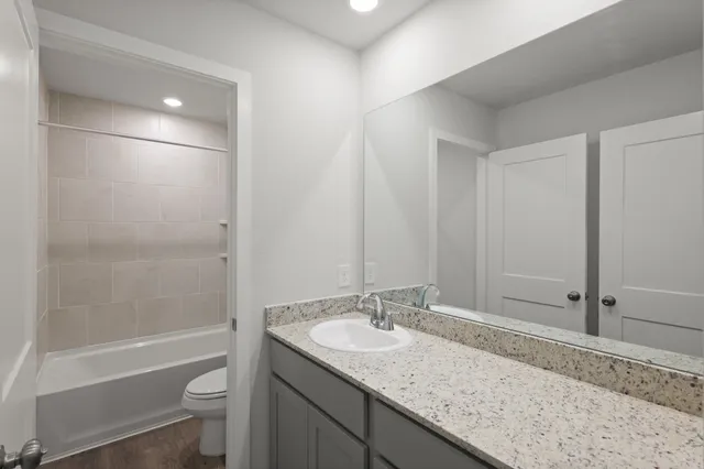 a bathroom with a granite countertop sink toilet and shower