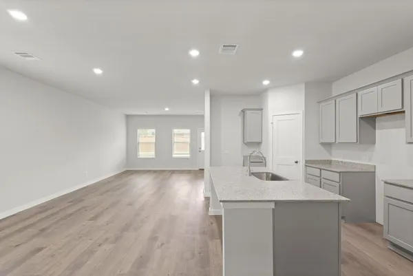 a kitchen with a sink dishwasher a stove and white cabinets with wooden floor