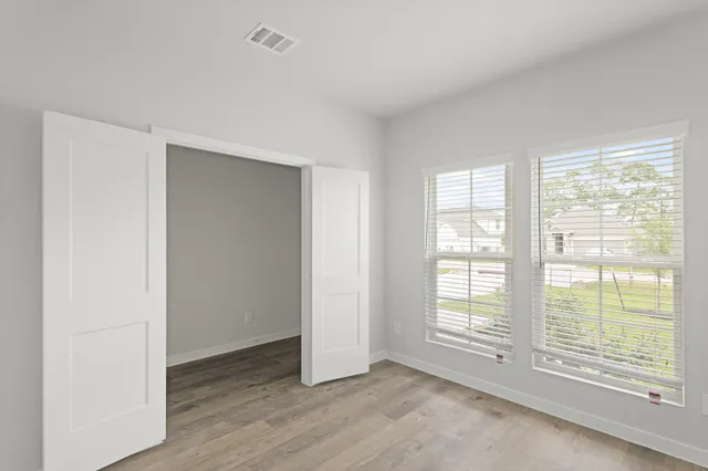 a view of an empty room with wooden floor and a window