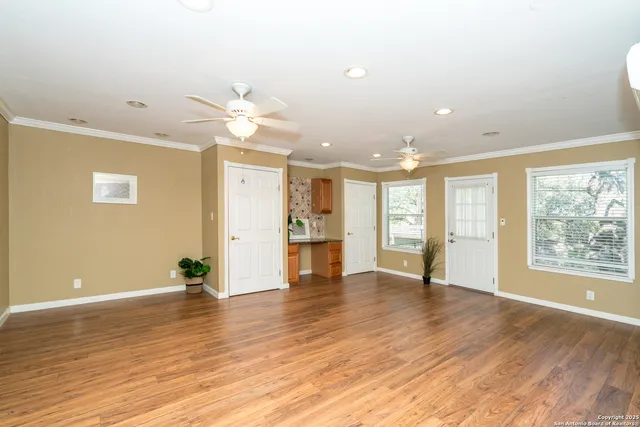 a view of an empty room with window and wooden floor
