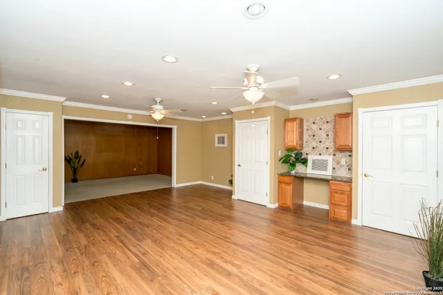 a view of a living room a kitchen with wooden floor and a kitchen space with a sink