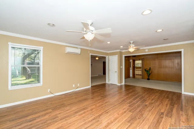 a view of an empty room with wooden floor and a window