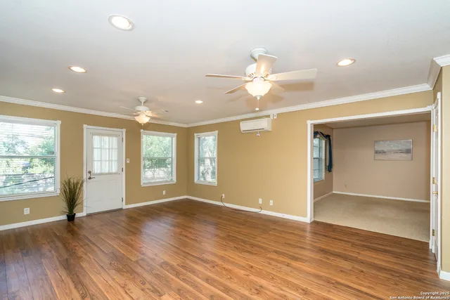 a view of an empty room with a window and wooden floor