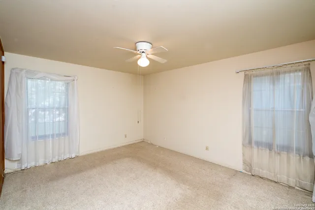 an empty room with closet area and fan