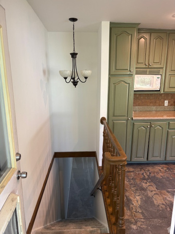 2313 150 East Bountiful, UT 84010 - Photo 26 of 39 Stairwell entrance featuring an ornate wood baluster, carpeted steps, and a decorative chandelier