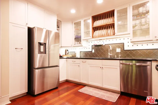a kitchen with granite countertop stainless steel appliances a refrigerator a sink and cabinets