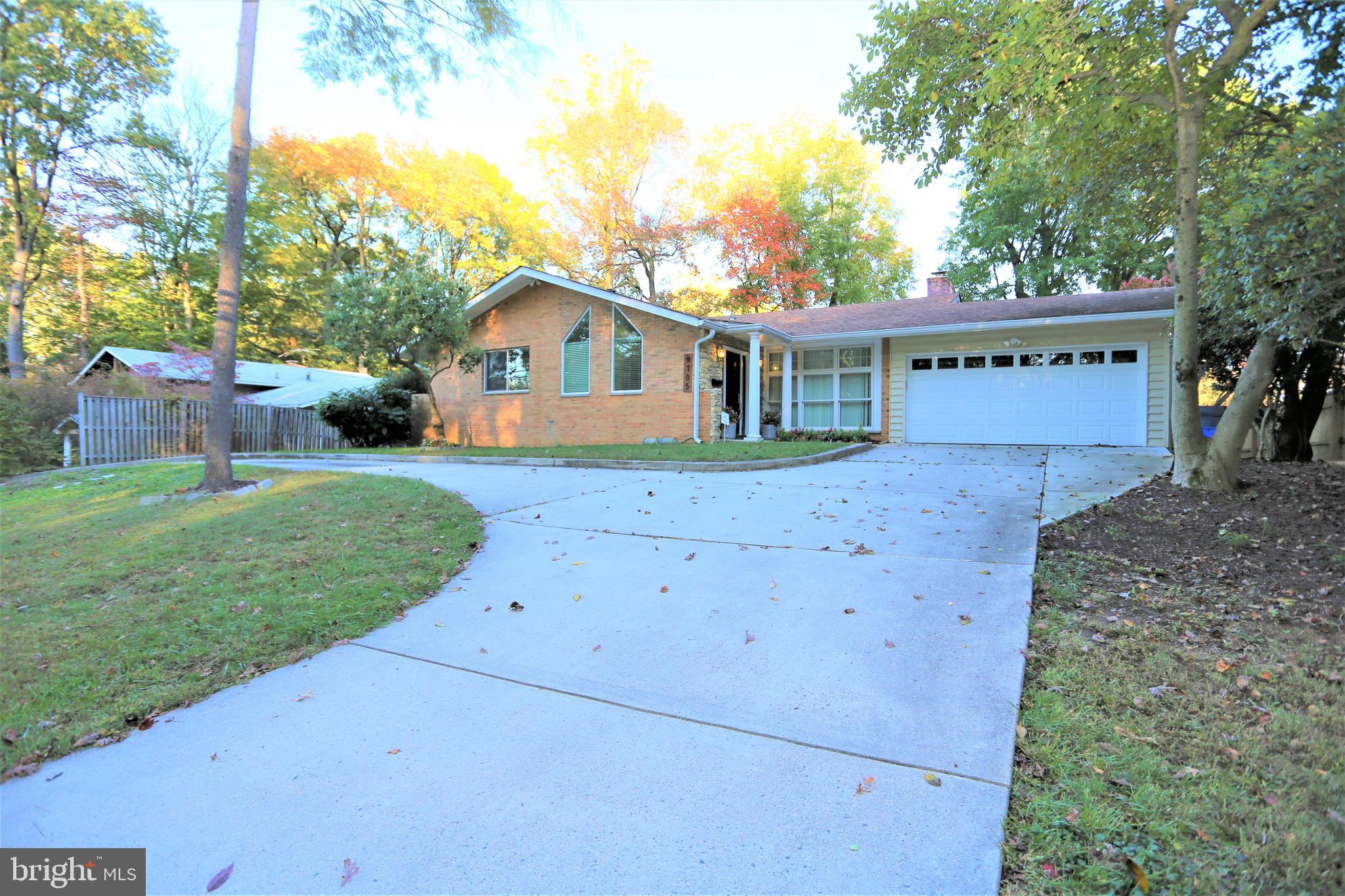 a view of a house with a yard and large tree