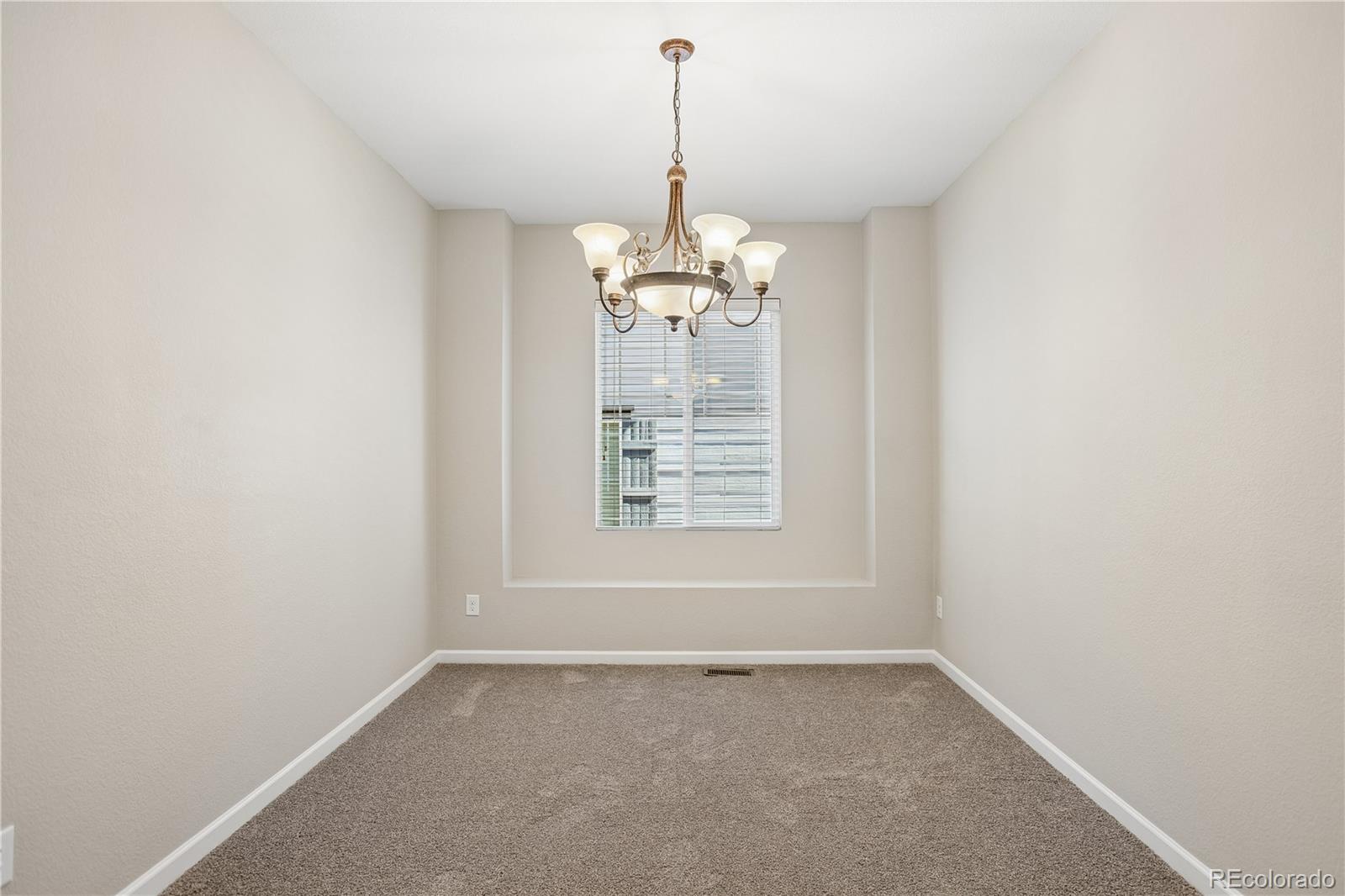 5031 South Rome Street Aurora, CO 80015 - Photo 24 of 39 en empty room with windows and chandelier