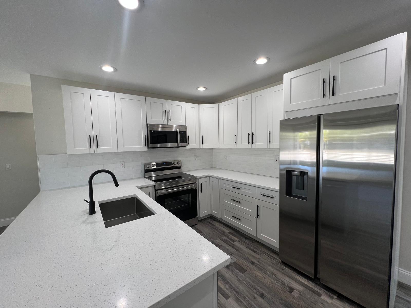 a kitchen with granite countertop a refrigerator stove and sink