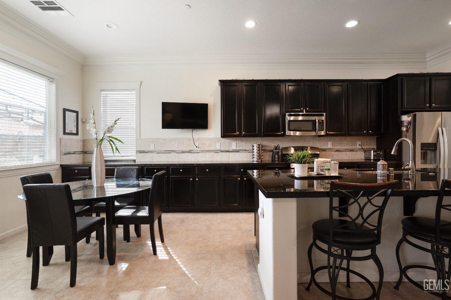 Undisclosed Address Bakersfield, CA 93314 - Photo 10 of 42 a kitchen with a table chairs refrigerator and microwave
