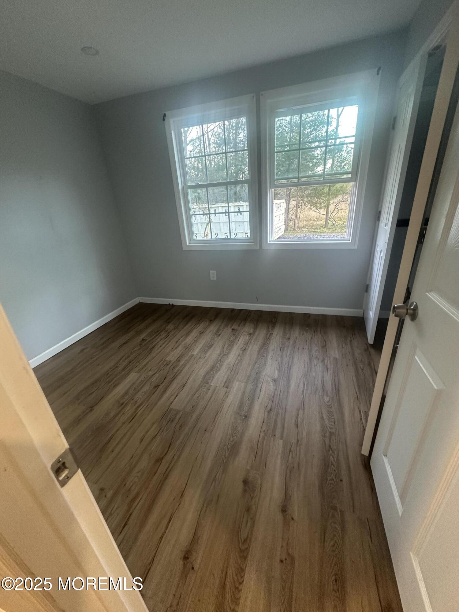 240 Perrineville Road Jackson, NJ 08527 - Photo 7 of 12 a view of an empty room with wooden floor and a window