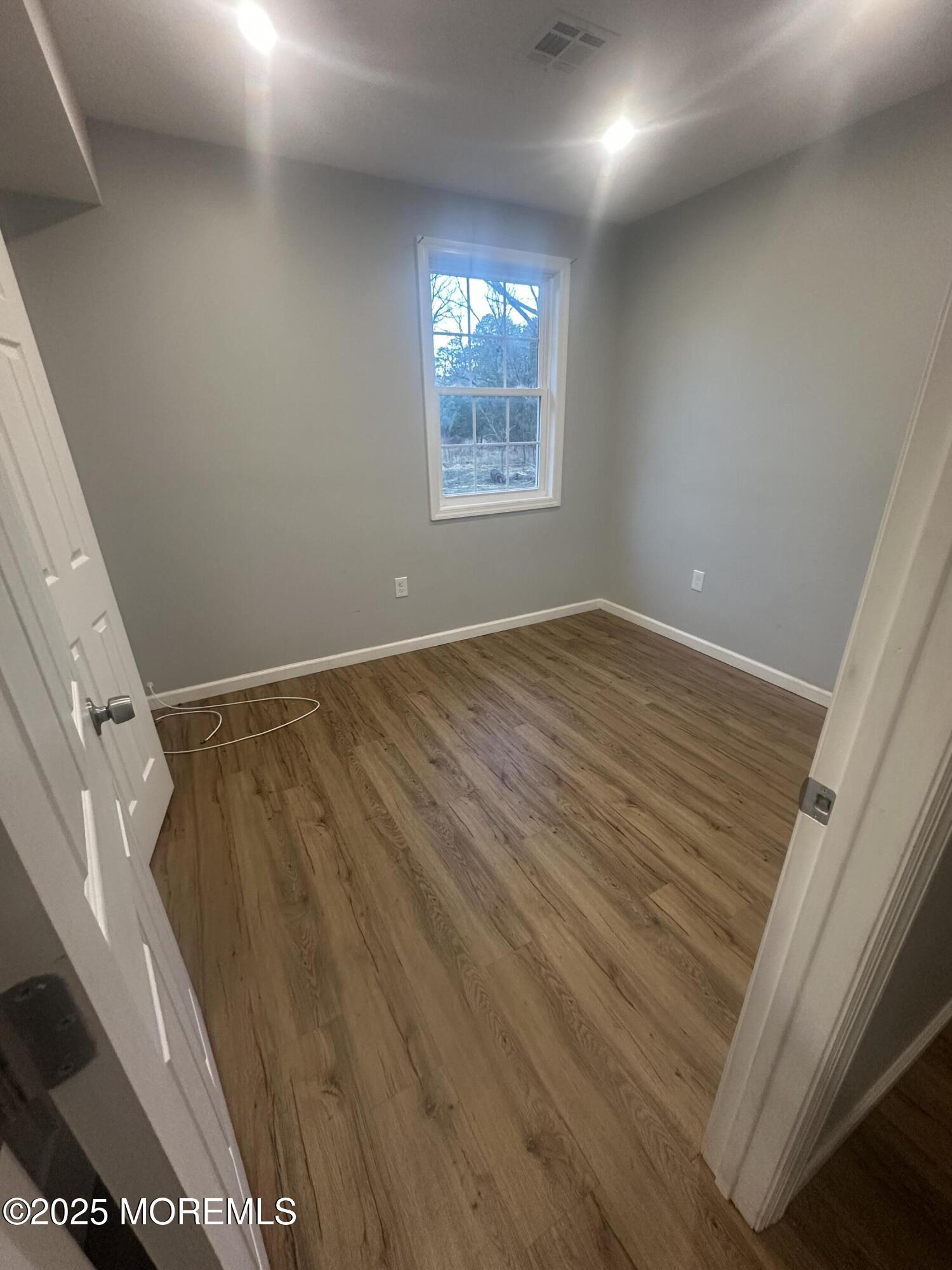 240 Perrineville Road Jackson, NJ 08527 - Photo 9 of 12 a view of an empty room with wooden floor and a window