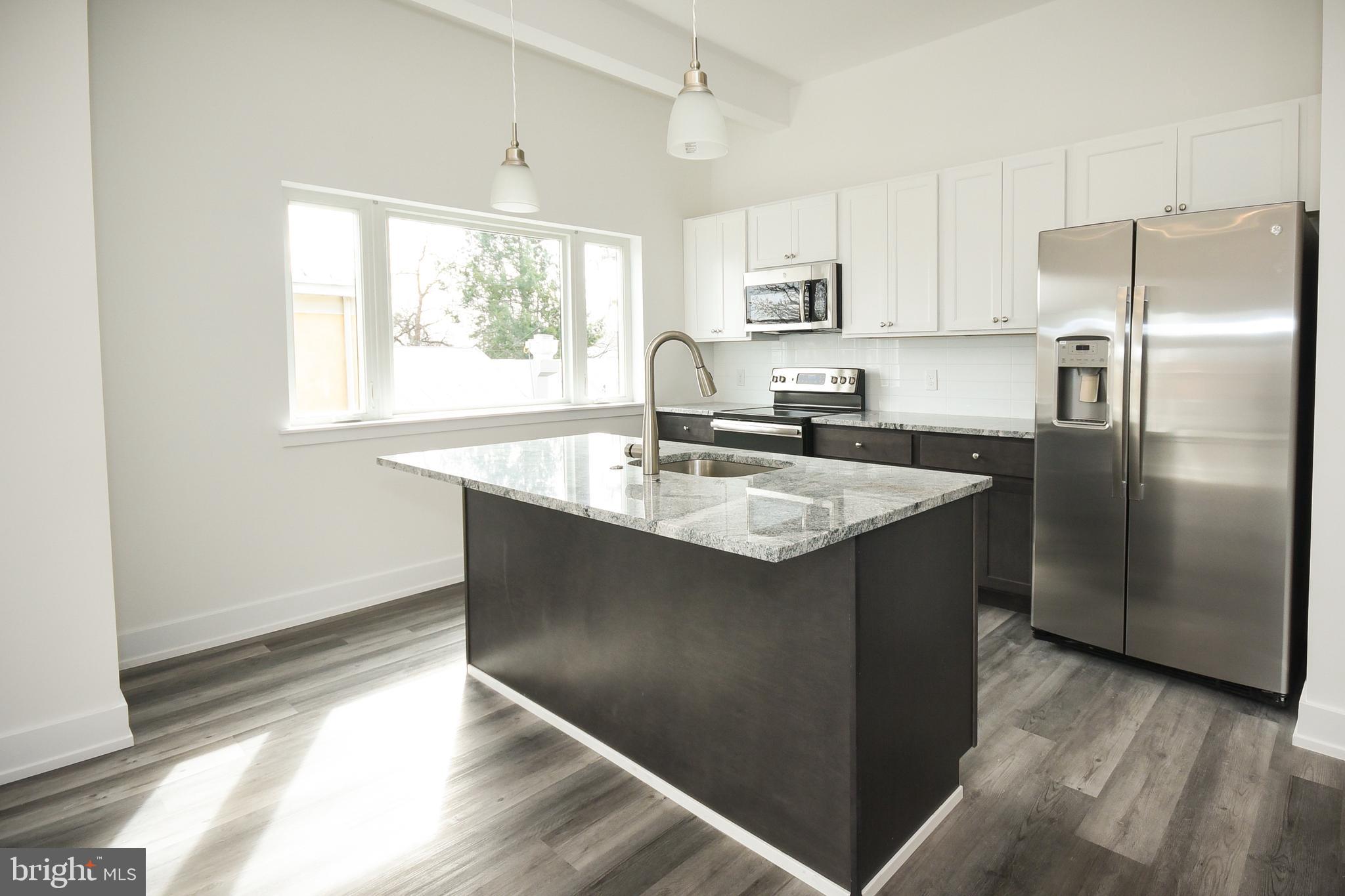 6162 Ridge Avenue, Unit 203 Philadelphia, PA 19128 - Photo 20 of 20 a kitchen with stainless steel appliances granite countertop a refrigerator a sink a stove and white cabinets with wooden floor