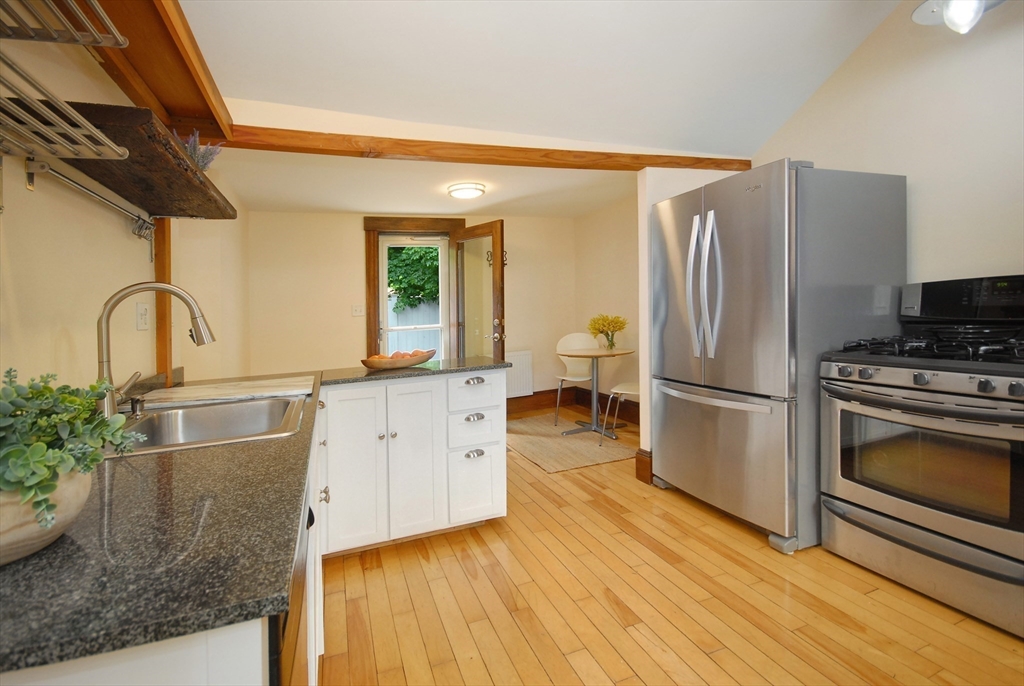 1832 Main Street Concord, MA 01742 - Photo 4 of 25 a kitchen with stainless steel appliances granite countertop a refrigerator a stove and a sink with wooden floor