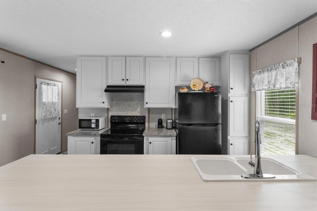 4686 C R 656 Webster, FL 33597 - Photo 11 of 32 a kitchen with granite countertop a refrigerator stove and sink