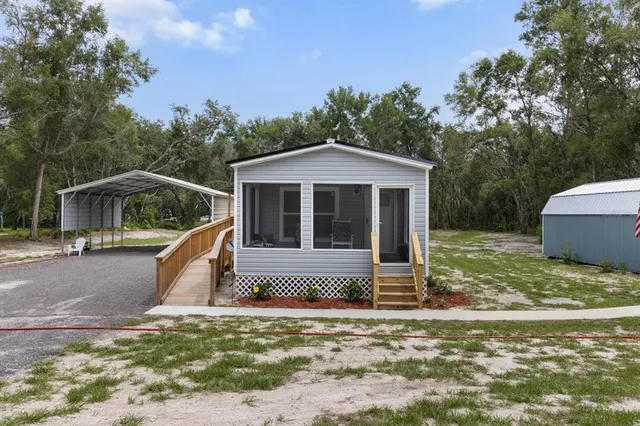 a view of a house with backyard and trees in the background