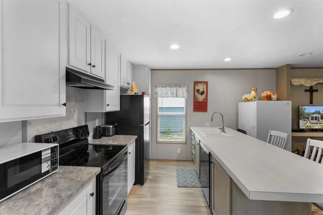 a kitchen with stainless steel appliances a stove a refrigerator a sink a stove and wooden cabinets