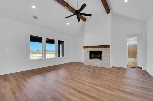a view of an empty room with window and wooden floor