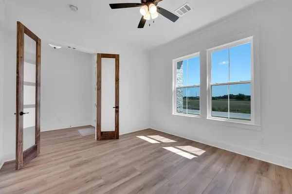 a view of empty room with wooden floor and fan