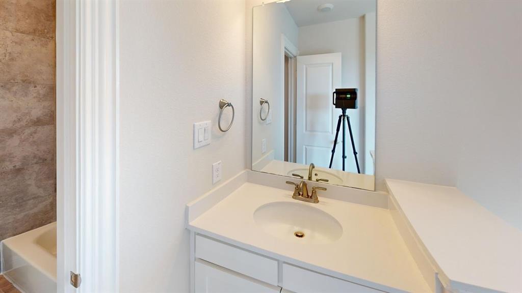 8407 Cornerstone Drive Rowlett, TX 75088 - Photo 4 of 25 Bathroom vanity featuring a white countertop with an integrated sink, brushed bronze faucet, and a wall-mounted mirror