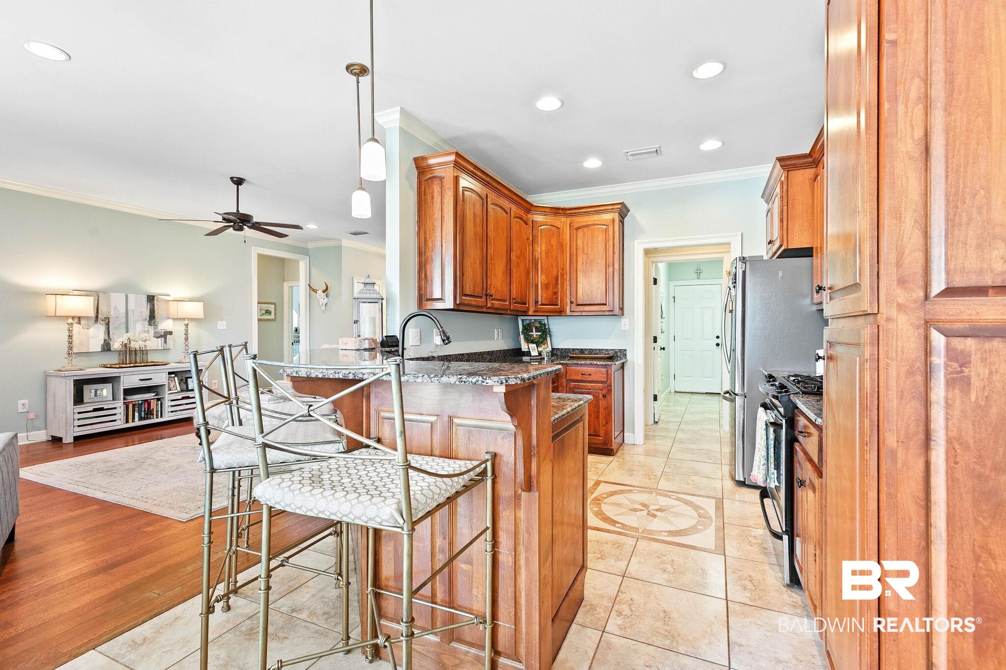 9522 Sanibel Loop Daphne, AL 36526 - Photo 16 of 43 Kitchen with crown molding, light tile patterned floors, stainless steel gas stove, brown cabinets, and decorative light fixtures