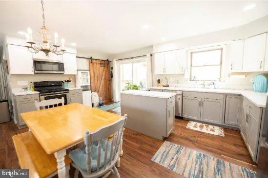 a kitchen with stainless steel appliances a stove a sink dishwasher a refrigerator with white cabinets and wooden floor
