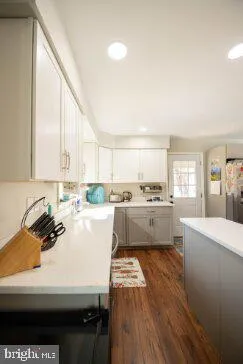 a kitchen with a sink a stove a refrigerator and white cabinets with wooden floor