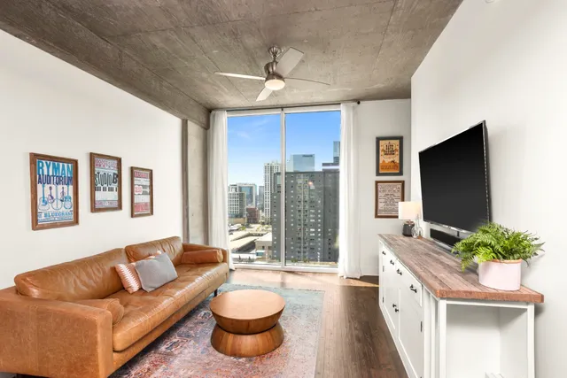 a living room with furniture a flat screen tv and a large window