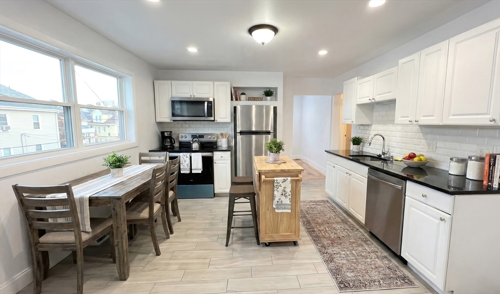 a kitchen with granite countertop a table chairs microwave and cabinets