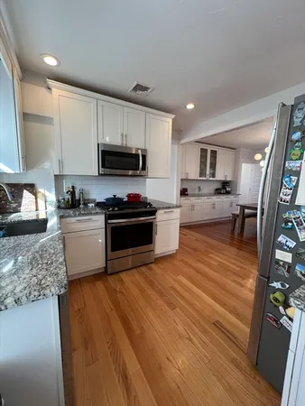 a kitchen with granite countertop a stove top oven a sink dishwasher and a refrigerator with wooden floor