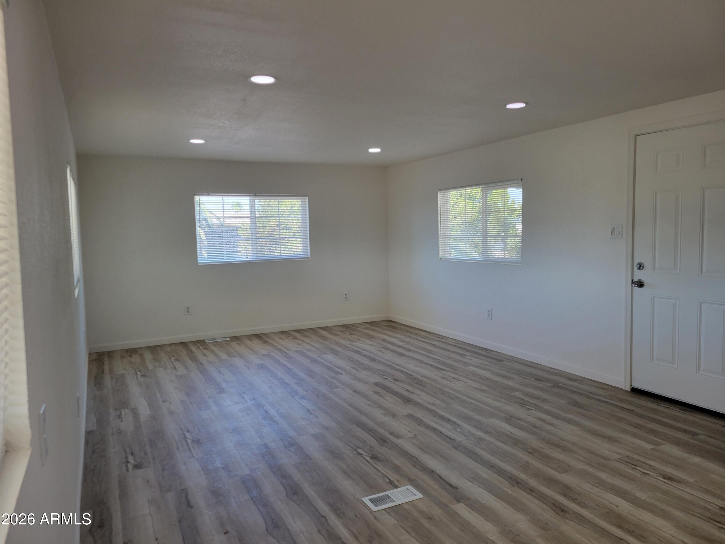 18026 North Cave Creek Road, Unit 1 Phoenix, AZ 85032 - Photo 5 of 14 an empty room with wooden floor and windows