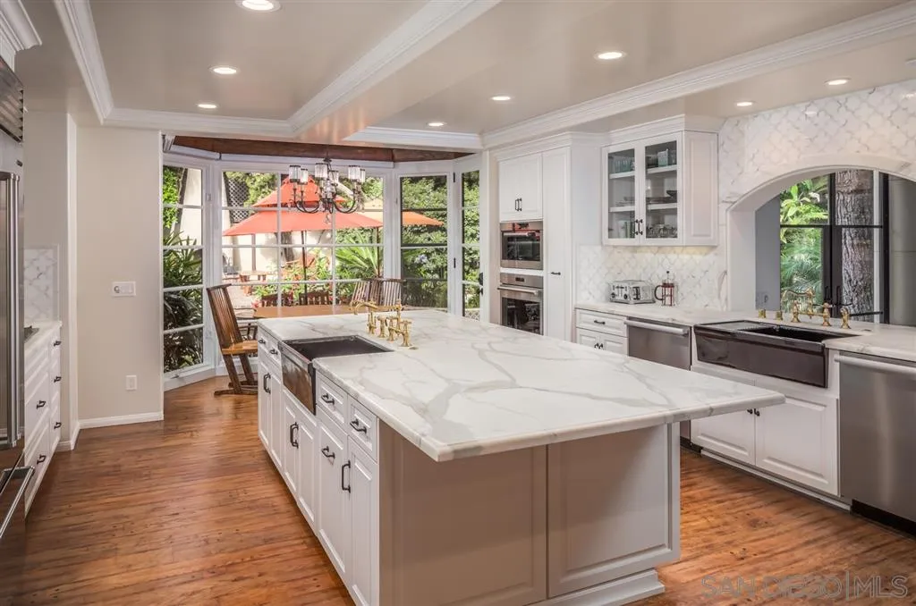 901 Highland Avenue Del Mar, CA 92014 - Photo 9 of 25 a large white kitchen with wooden floors and stainless steel appliances