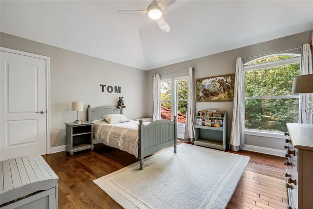 a spacious bedroom with a bed and a dresser with wooden floor