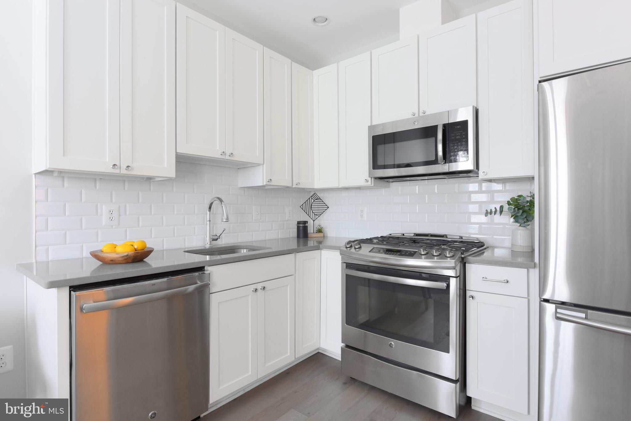 3921 Fulton Street Northwest, Unit 3 Washington, DC 20007 - Photo 7 of 24 a kitchen with white cabinets and stainless steel appliances
